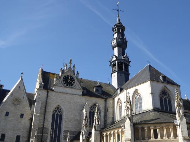 Foto van een grote kerk met een donkergrijs dak en witte muren: de parochiekerk in Zoutleeuw. Waar je meerdere sporen van lepra kan terugvinden.